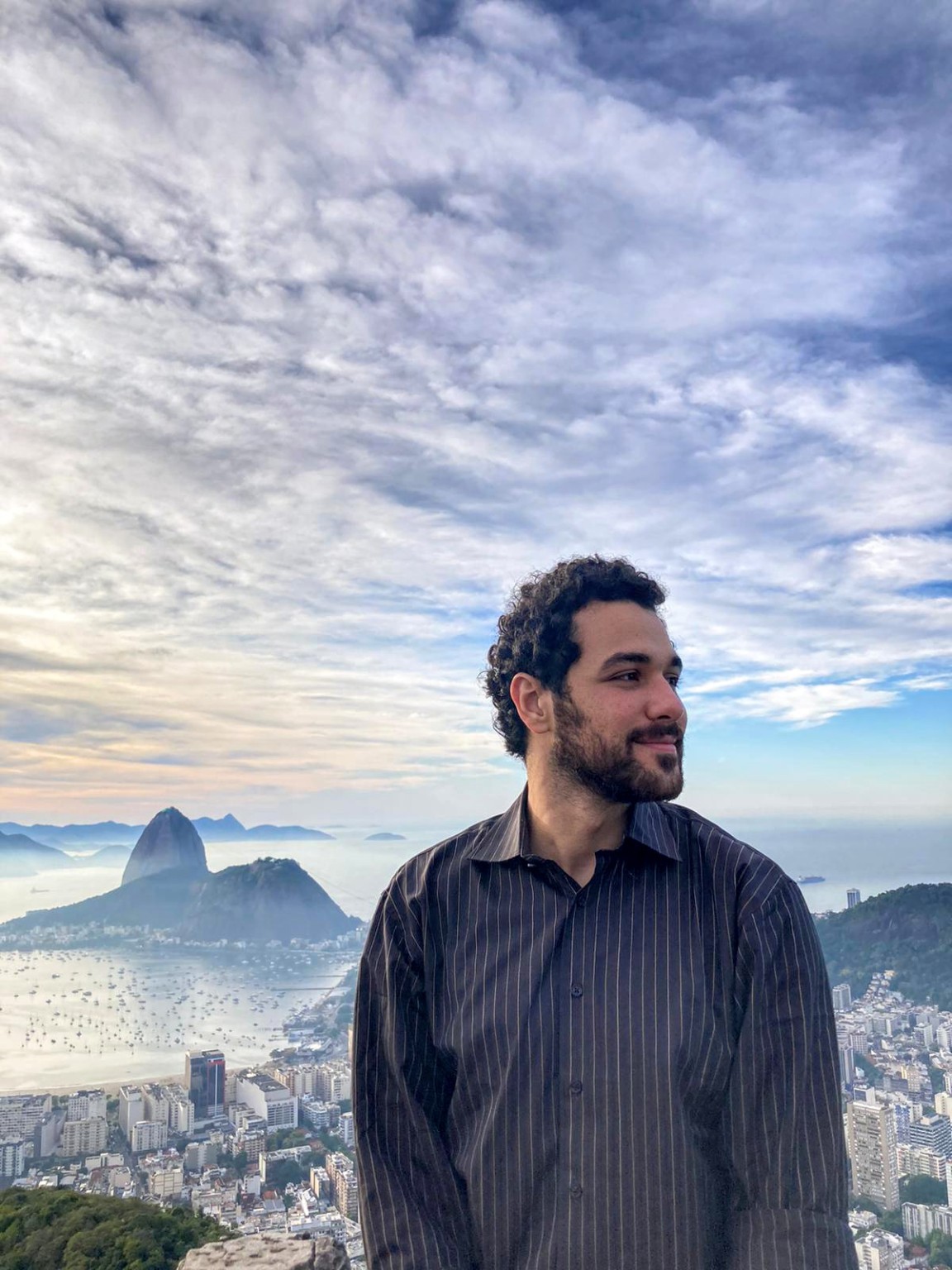 Hapi, founder and educator of Álquimia, with a coastal city and mountains behind him